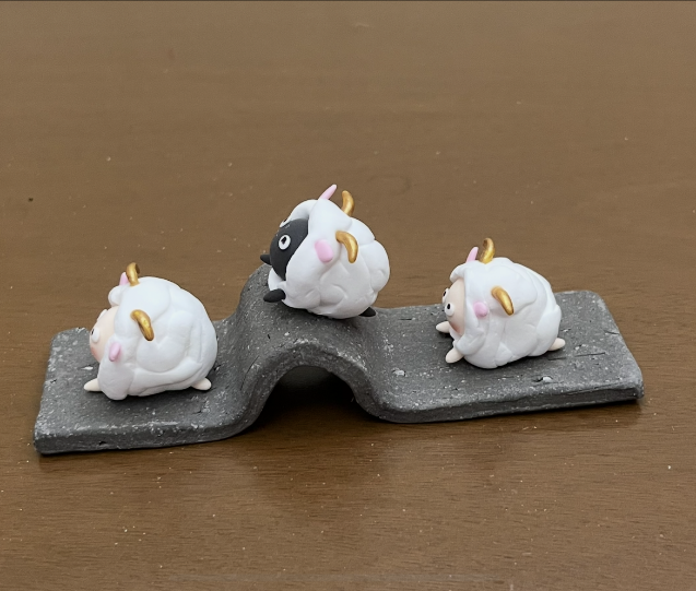 瓦の上に並ぶ、表情豊かな3匹の羊の粘土細工